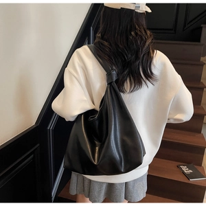 Détail d'un sac cabas hobo noir minimaliste avec une bandoulière à nœud élégante et moderne