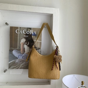 Détail du sac seau tissé à la main jaune moutarde avec un joli pendentif ours en peluche