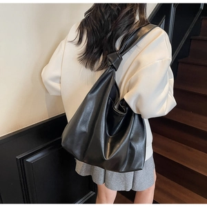 Détail d'un grand sac cabas noir avec bandoulière nouée et texture en similicuir souple