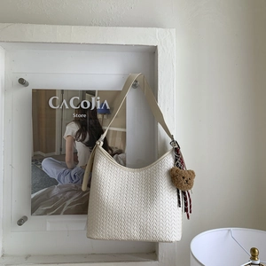 Détail de texture du sac seau tressé blanc avec un pendentif mignon en forme d'ours en peluche