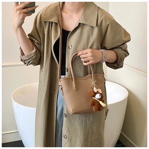 Detailansicht der braunen Mini-Tasche aus Leder mit Narbenstruktur und Bärenanhänger