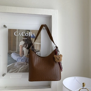 Vue détaillée d'un sac seau marron tissé à la main avec un joli pendentif ours en peluche