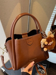 Brown litchi grain tote bag with handle, shoulder strap and plush monster charm