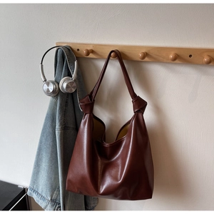 Détail d'un grand sac cabas marron avec poignée nouée sur un crochet en bois