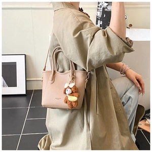 Detail der beigen Leder-Einkaufstasche mit Plüschbär-Anhänger und abnehmbarem Gurt