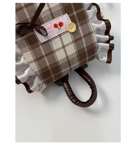 Detail der karierten Beuteltasche mit Kirschstickerei, Spitzenbesatz und Ledergriff