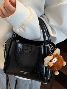 Chic black lychee grain leather tote bag with long strap and cute plush monster charm