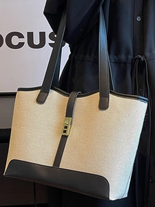 Large beige canvas tote bag with black leather trim and elegant gold metal buckle