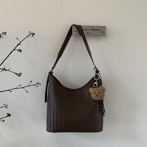 Détail du sac seau marron foncé tissé à la main avec pendentif ours et texture