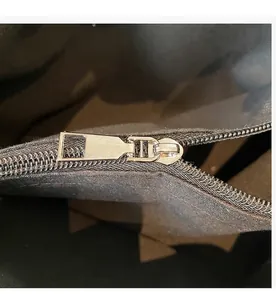 Detalle de la cremallera de metal plateado liso en un bolso de mano negro grande