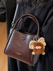 Dark brown lychee pattern leather handbag with gold logo and cute plush ball charm