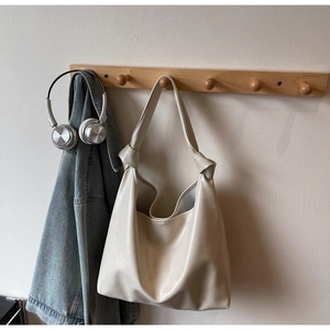 Détail du sac hobo en cuir PU crème avec une bandoulière nouée élégante sur un support