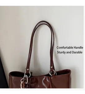 Detalle de bolso tote marrón oscuro con anillos de metal plateado y asas largas fuertes