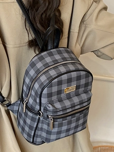 Chic black and grey checkered mini backpack with silver metal logo on a model