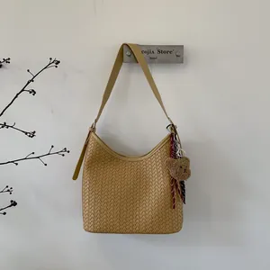 Détail du sac seau jaune tissé à la main avec breloque ours en peluche et bandoulière fine