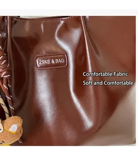Detalle del bolso tote de cuero PU marrón oscuro con logo y un lindo oso de peluche