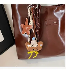Detalle de un osito de peluche y colgante de estrella en el asa de un bolso tote