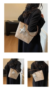 Detail of beige floral tote bag with brown leather straps and silver star charm