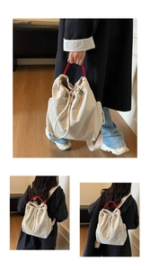 Detail view of cream drawstring backpack with contrasting bright red woven handles