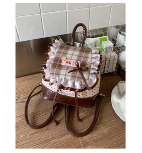 Detail des süßen karierten Rucksacks mit weißem Rüschenrand und Kirschstickerei