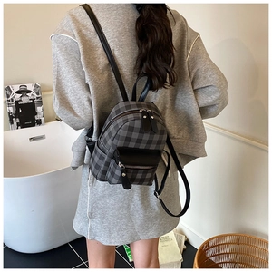Schicker Minirucksack mit schwarz-grauem Karomuster und Lederriemen am Modell präsentiert