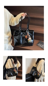 Detail of black glossy tote bag featuring a metal logo and star-shaped bag charms