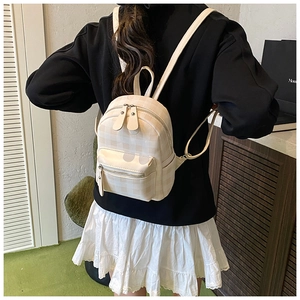 Detailansicht des cremefarbenen Mini-Rucksacks mit Karomuster und Metallreißverschluss am Model
