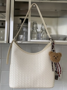 Sac hobo blanc tressé avec porte-clé ours en peluche marron sur meuble de cuisine