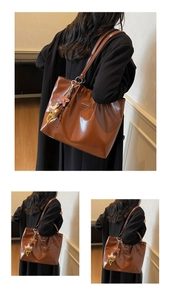 Detail view of the brown leather tote bag side with star and bear pendant charms