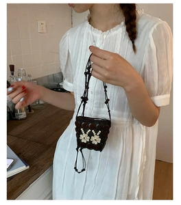Detail of bohemian handmade woven mini crossbody bag featuring white floral accents