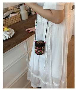 Detail of bohemian hand-woven mini bag with colorful beads and floral crossbody strap
