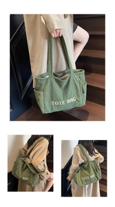 Detail of green corduroy tote bag showing side pockets and embroidered letter texture