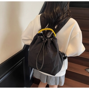 Detail of black drawstring backpack featuring a bright yellow braided rope handle
