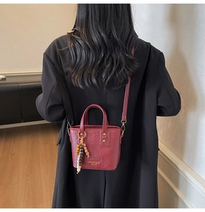 Details einer weinroten Vintage-Beuteltasche mit Tragegriffen und Schultergurt