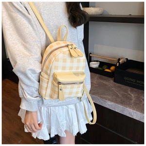 Detail eines Mini-Rucksacks mit gelbem Karomuster, Reißverschlusstasche und Tragegriff
