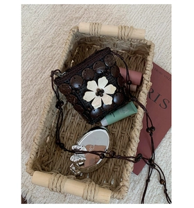 Detail of bohemian mini bag with white crochet flower and beads in lifestyle setting