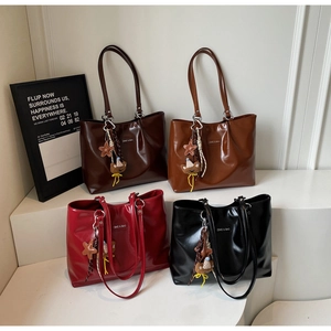 Detail shot of four glossy leather tote bags in various colors on a display stand