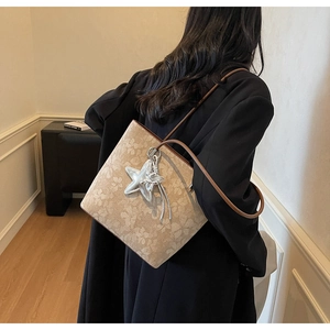 Detail view of printed tote bag with leather straps and silver star pendant on shoulder