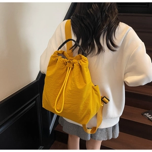 Detail of a bright yellow nylon drawstring backpack with black braided handle and straps