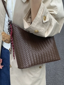 Sac seau tressé marron foncé avec pendentif ours, porté par un mannequin en manteau