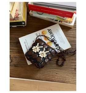 Detail of bohemian handmade mini bag with ivory floral accents on vintage wood beads