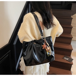 Detail of black PU leather tote bag with star charm and rectangle logo on front