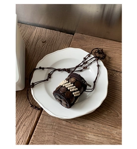 Macro detail of handmade bohemian mini bag with coconut shell decorations and wooden beads