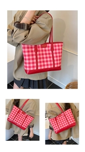 Detailed view of red and pink plaid tote bag with metal logo and slender shoulder strap