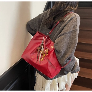 Detail of red patent leather tote bag with star bear charm on wooden stairs