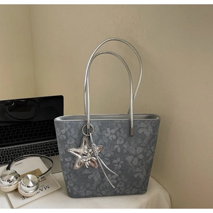 Detailed view of grey printed tote bag with silver star charm and floral texture
