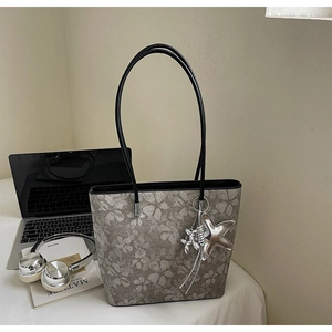 Detailed shot of floral tote bag with a silver star charm on an office desk