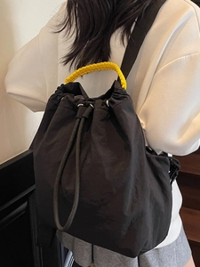 Minimalist black drawstring backpack with bright yellow handle for daily travel
