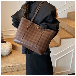 Detail view of large brown checkerboard tote bag with gold metal logo and leather straps
