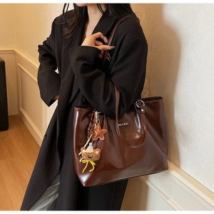 Detail of dark brown leather tote bag with star and bear charms and SKE & BAG logo